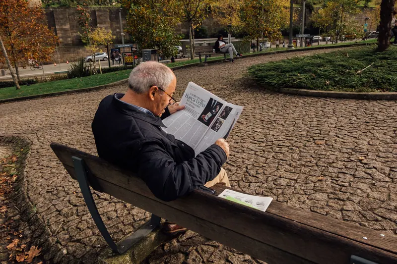 A resident with the newspaper on a bench