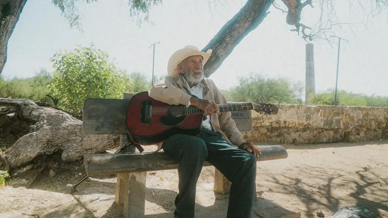 A resident playing guitar on a bench