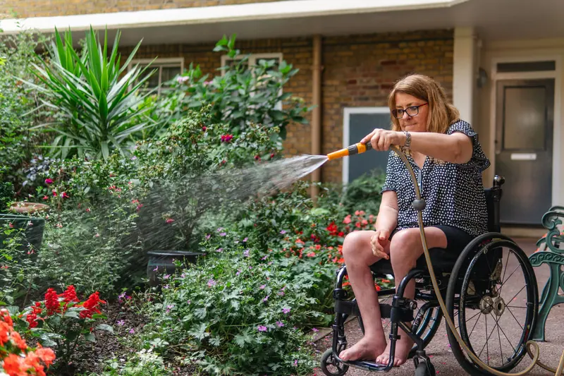 A resident watering the flower beds from her wheelchair
