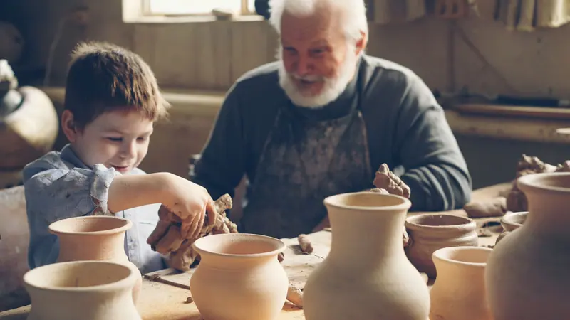 A grandfather and grandson finishing pots together