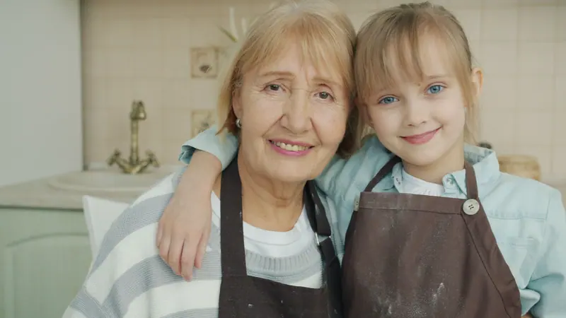 A resident and her granddaughter in matching aprons