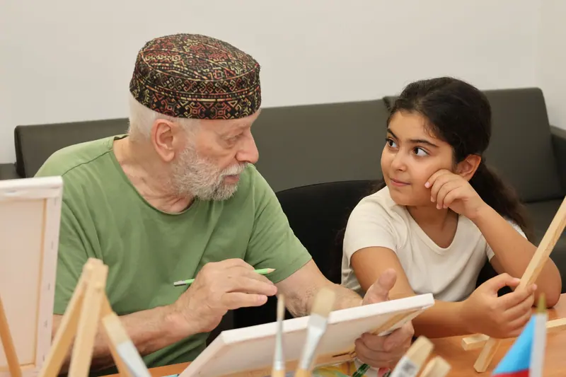 A grandfather painting with his granddaughter