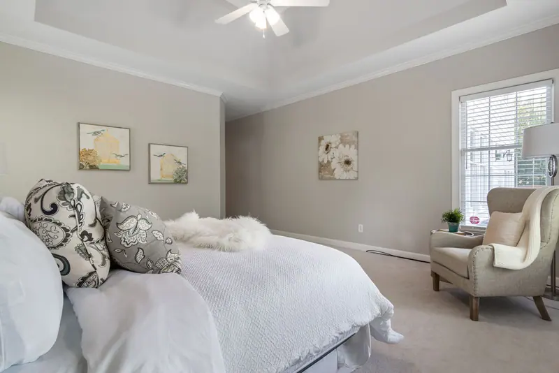 Bright, modern bedroom interior with bed, armchair, and stylish decor.