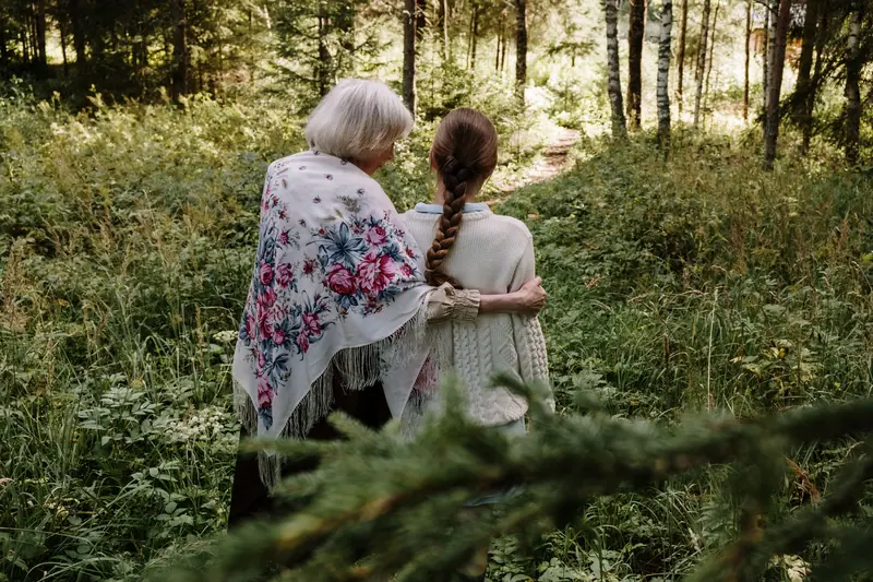 A grandmother and granddaughter walking in the woods