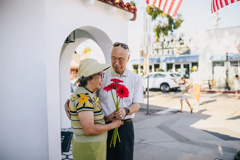 A husband handing his wife a bouquet of red flowers
