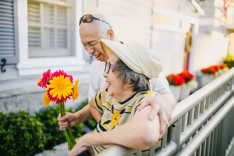 A couple sharing a laugh on their porch with a handful of zinnias