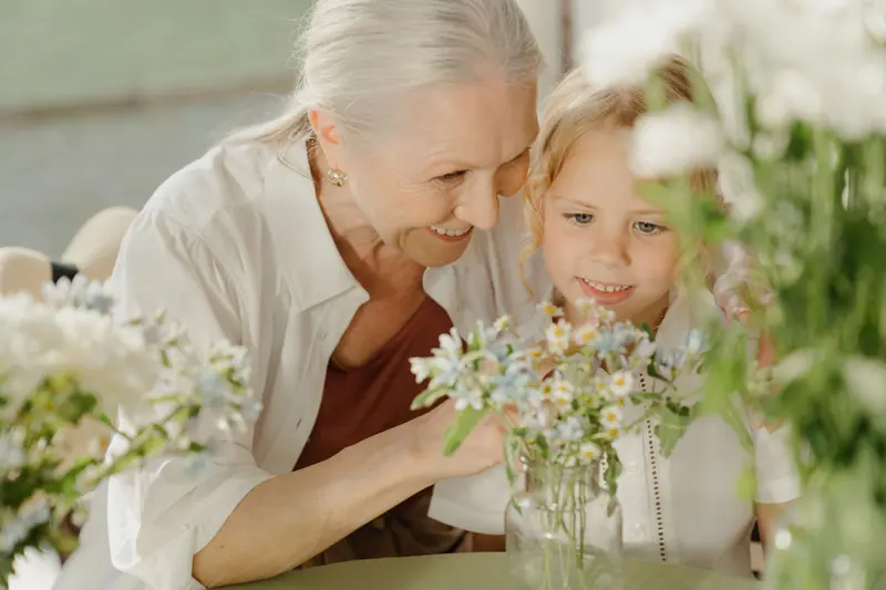 A resident and her granddaughter arranging flowers at the table