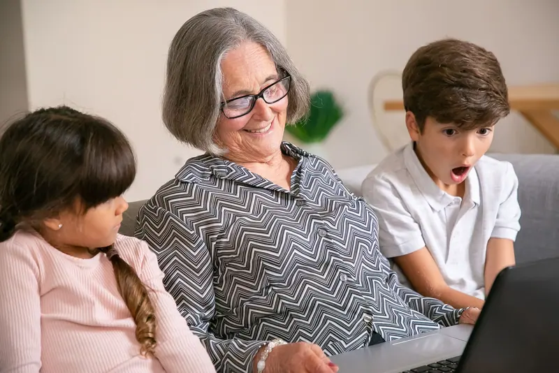 A grandmother showing her grandkids something on the laptop