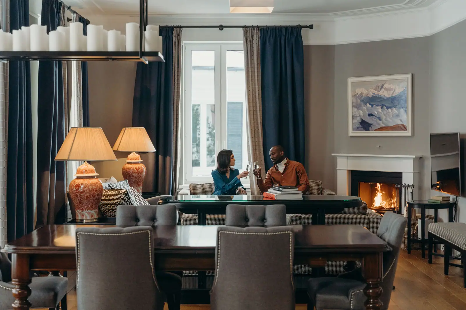 A couple sharing wine by the fireplace in their apartment