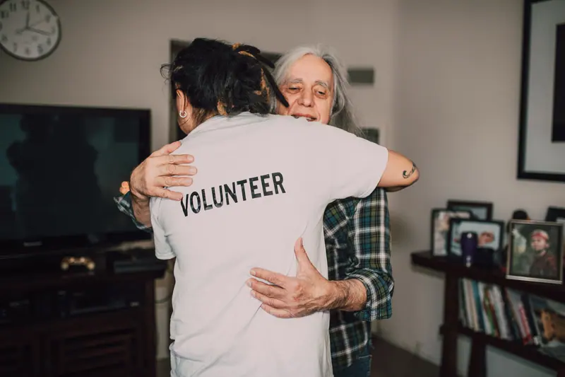A volunteer hugging a resident