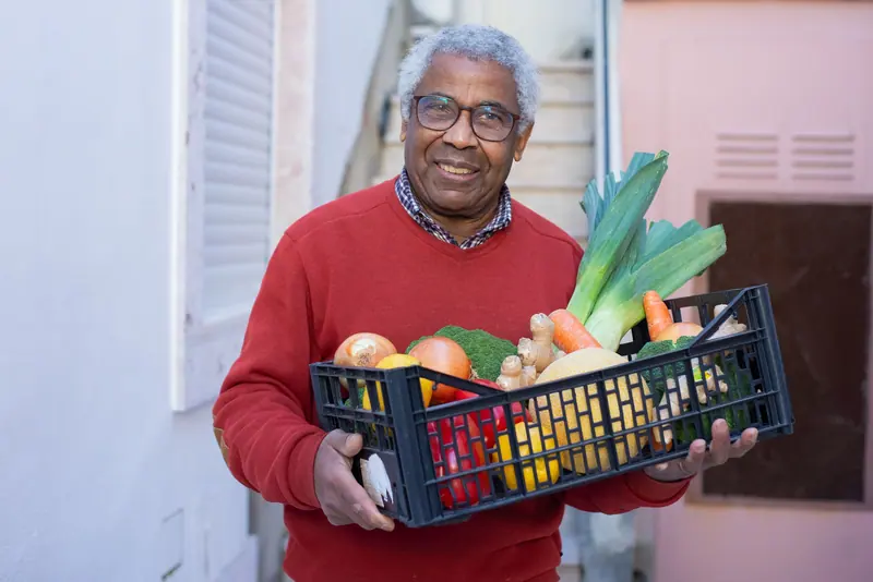 A resident with a crate of vegetables
