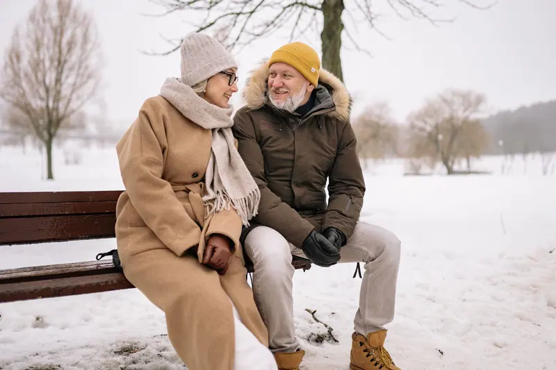 A couple bundled up on a snowy bench