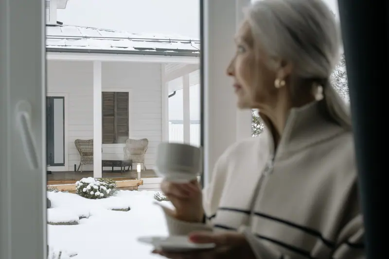 A resident with her morning coffee, watching the first snow on the cottage porch