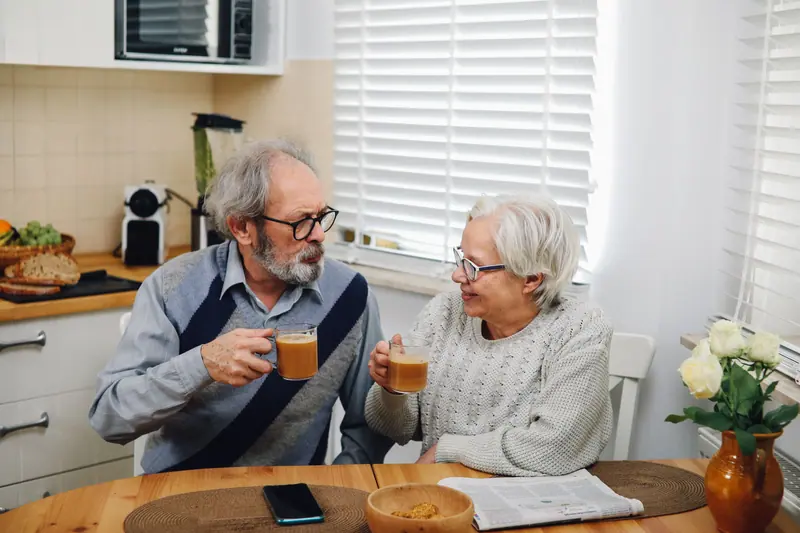 A husband and wife sharing tea at their kitchen table