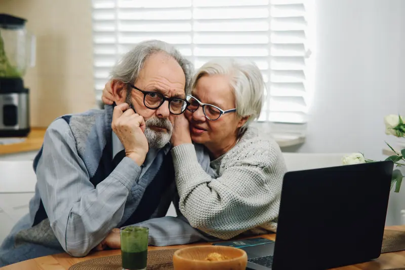 A husband and wife leaning close at the breakfast table