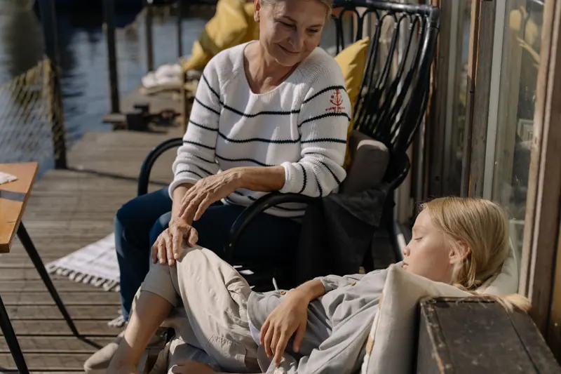 A grandmother resting on the patio with her sleeping grandchild