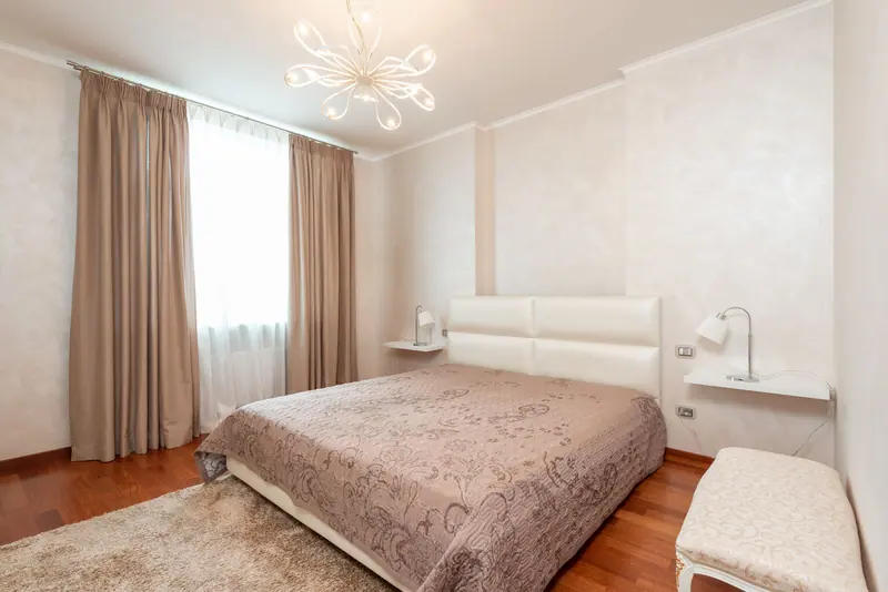 A cozy and modern beige bedroom featuring elegant decor and furnishings.