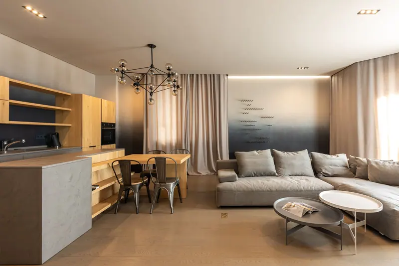 Stylish contemporary living room with an open kitchen featuring wooden accents and luxurious sofa.