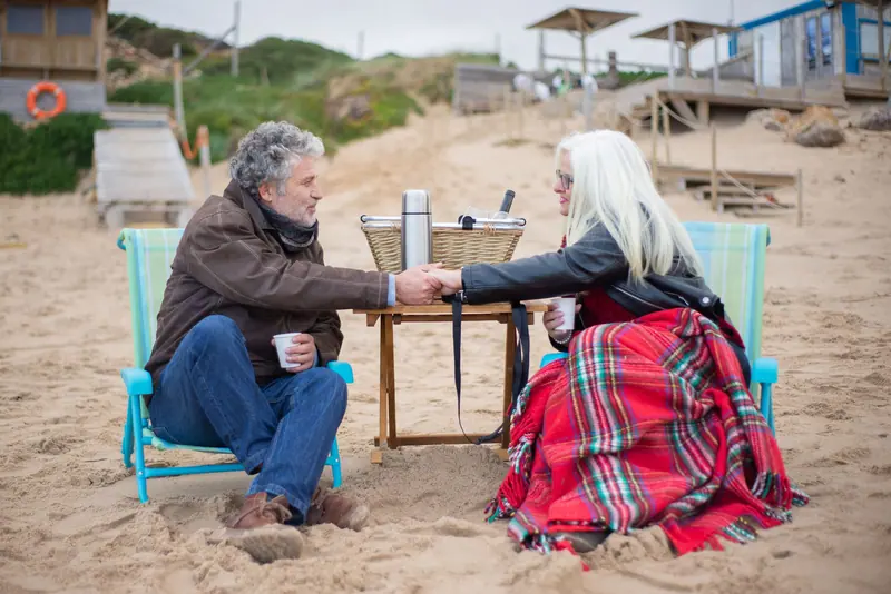 A couple sharing coffee on the sand