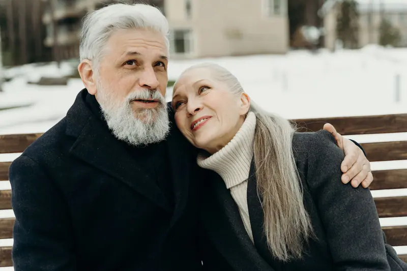 A couple keeping warm on a winter bench