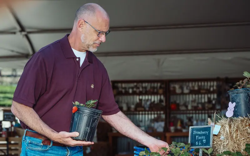 A resident choosing a plant in the greenhouse