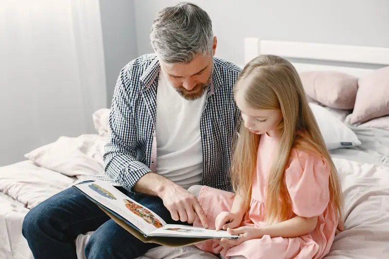 A grandfather reading with his granddaughter