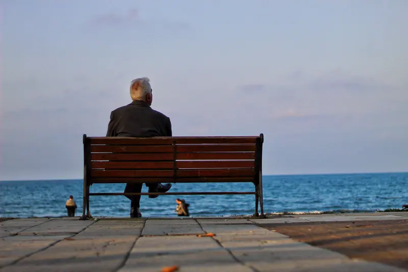 A resident on a bench facing the sea