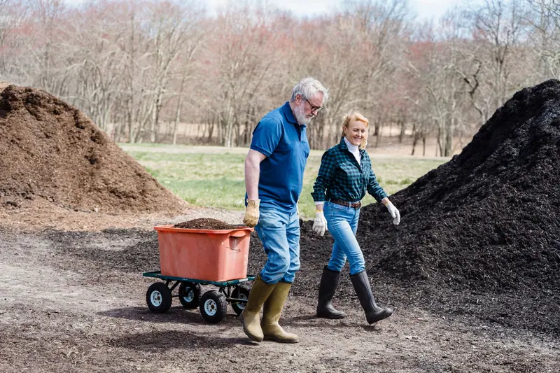 A couple hauling a wheelbarrow of soil to the beds