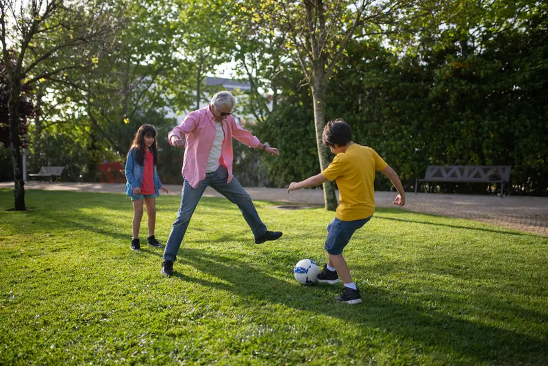 A grandfather playing soccer with the grandkids