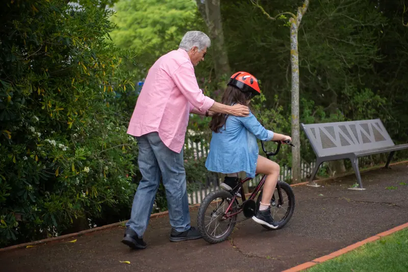 A grandfather helping his granddaughter ride