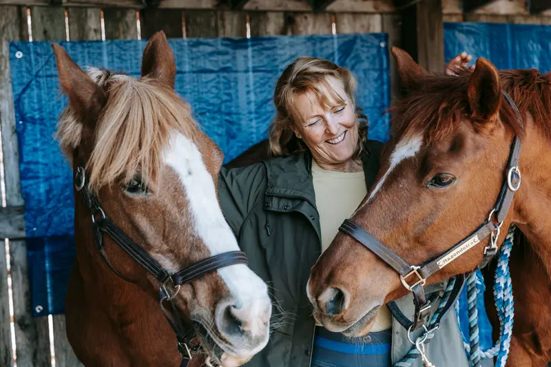 A resident with two horses in the barn