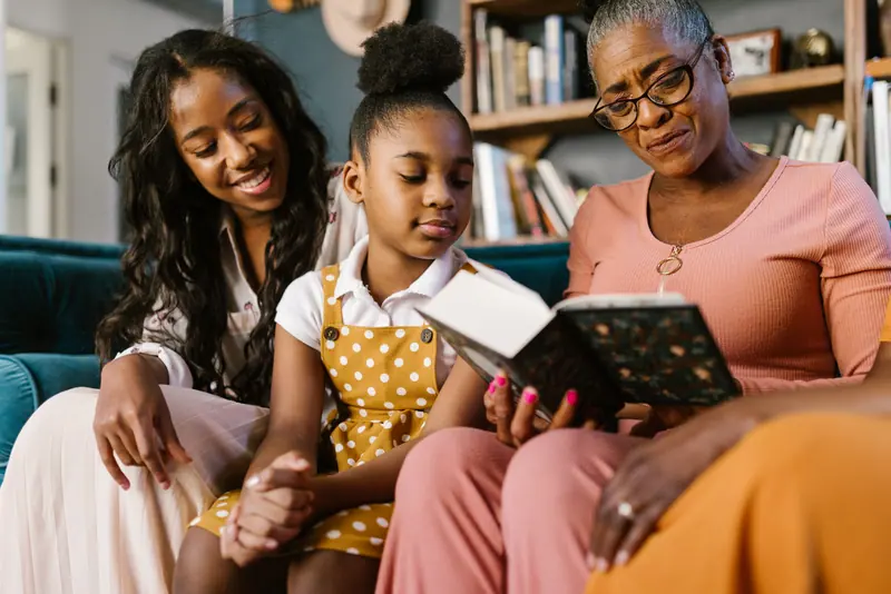 A grandmother reading aloud to her daughters and granddaughter