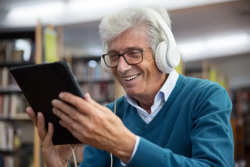 A resident with a tablet and headphones in the library