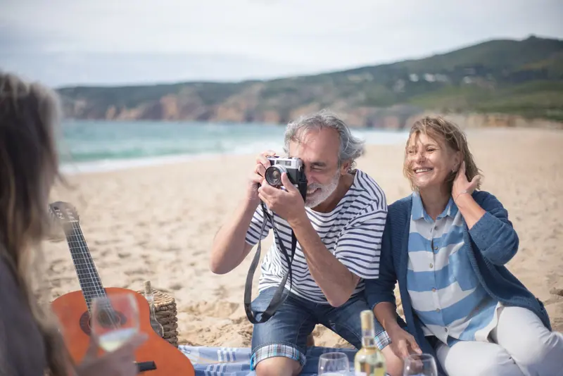 Friends at a beach picnic with a camera and a guitar