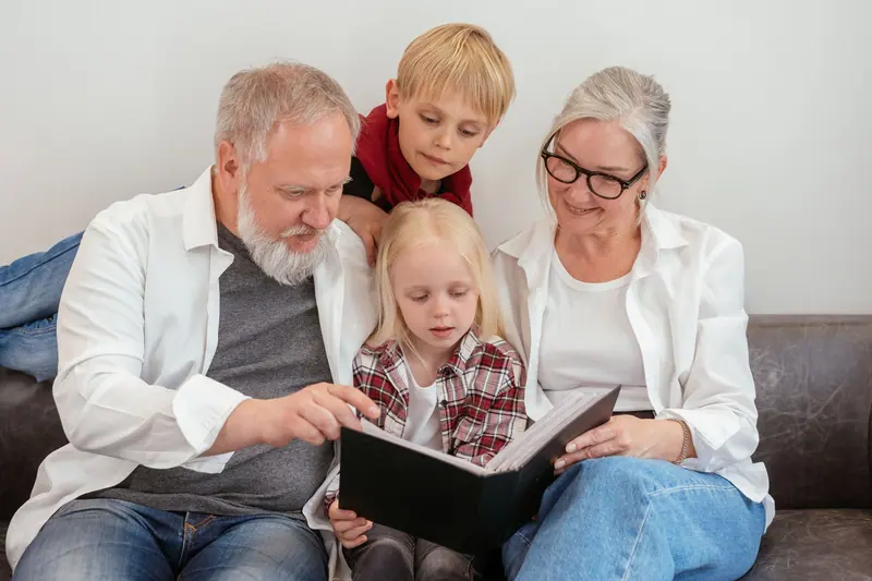 Grandparents paging through the family album with their grandchildren