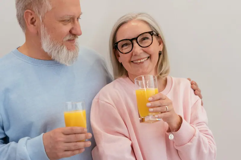 A couple toasting with orange juice at breakfast