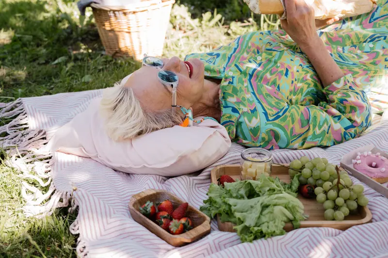 A resident resting on a picnic blanket with strawberries and grapes