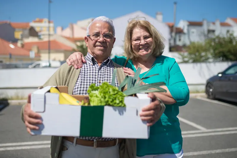 A couple bringing home a box of fresh produce