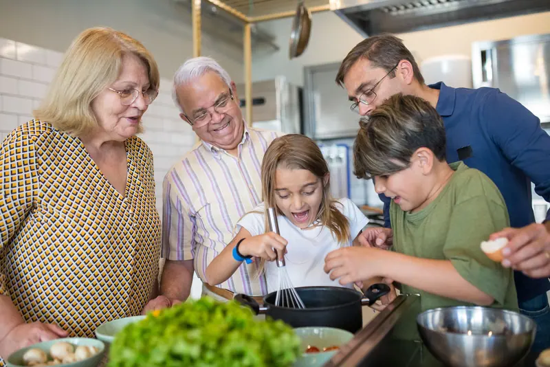 Three generations cooking together in a cottage kitchen