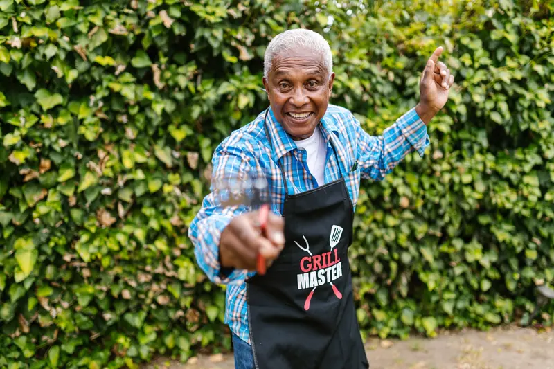 A resident pointing at the camera with a grin while he works the grill
