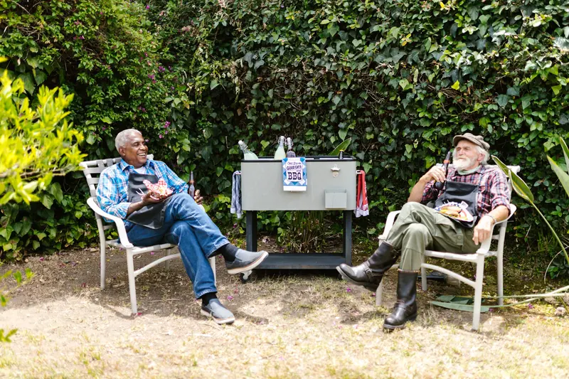 Two neighbors relaxing in lawn chairs by the cooler