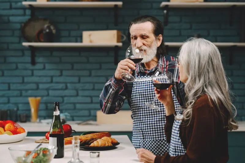 A couple sharing a glass of red while they cook