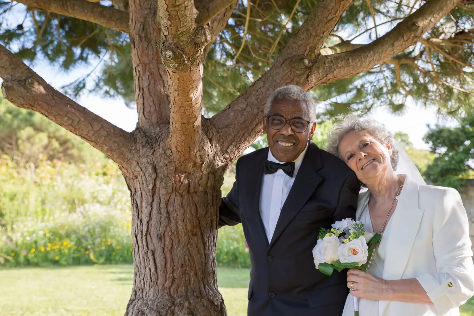 A husband and wife posing beneath the big pecan tree on the lawn after renewing their vows
