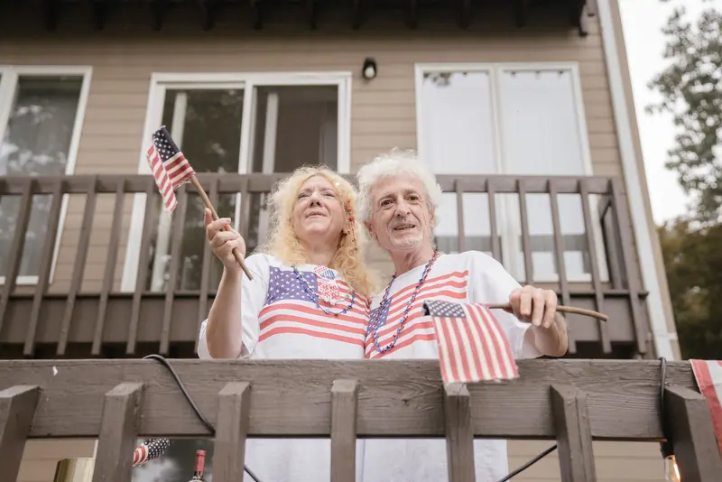A couple waving flags from their porch on the Fourth