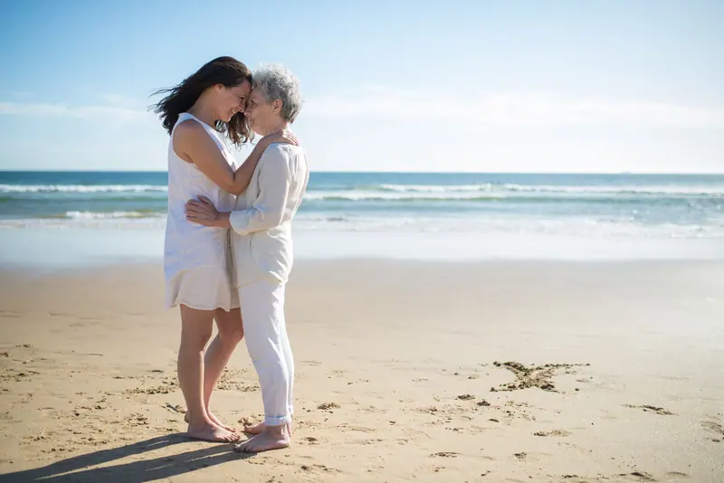 A mother and daughter embracing by the water