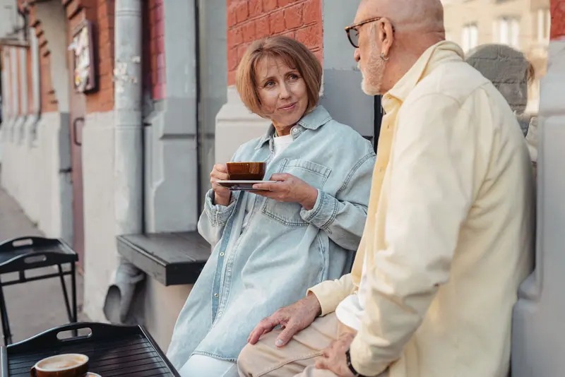 A couple talking over coffee on the patio outside the Grill