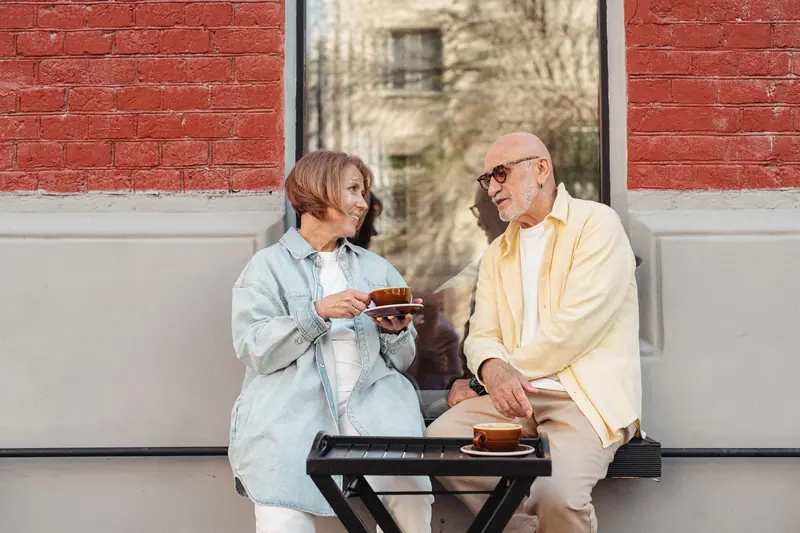 A couple with coffee against the brick wall of the Commons