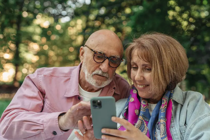 A couple sharing their phone on a bench