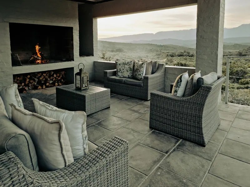 Inviting patio with stylish wicker furniture and a lit fireplace, showcasing South Africa's landscape.