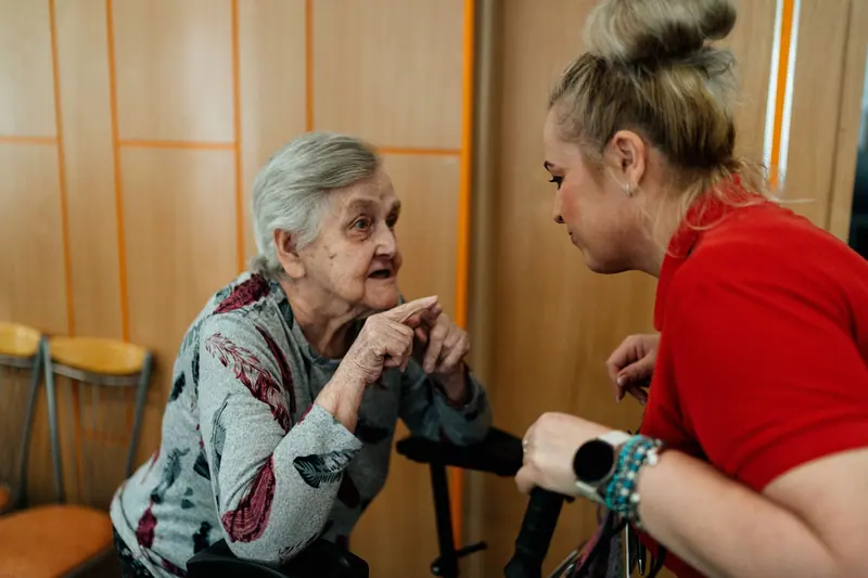 A caregiver kneeling to listen as a resident tells a story